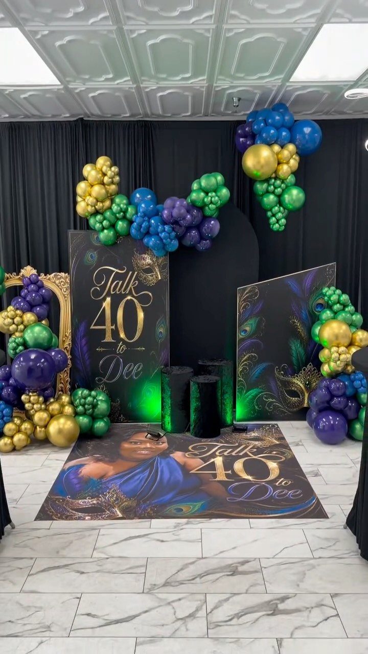 Gold, blue, and green balloon arches surrounding a 40th birthday backdrop and floor wrap.