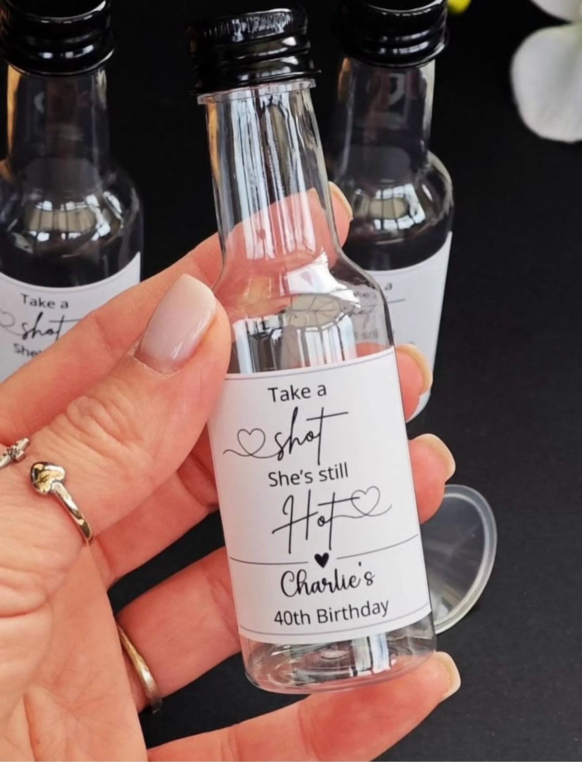 Small glass bottle with a custom 40th birthday label held by a hand.