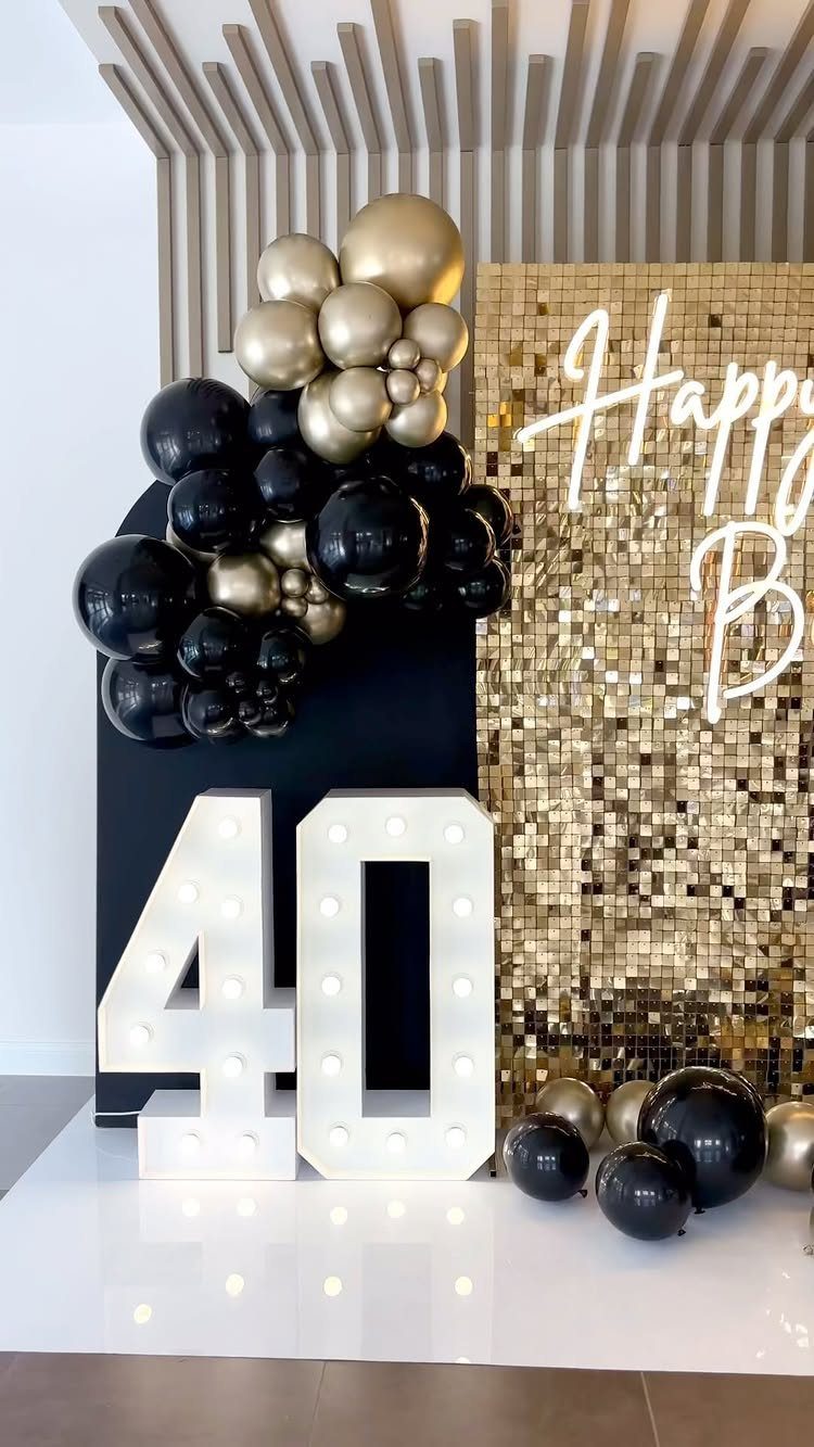 Large illuminated number 40 with gold sequin backdrop and black and gold balloons.