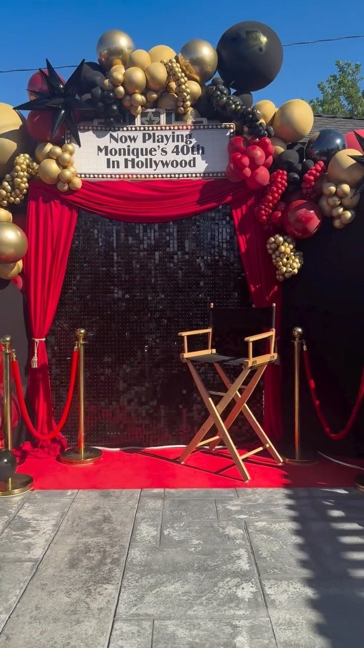 Movie themed 40th birthday setup with red carpet, director's chair, and balloon arch.