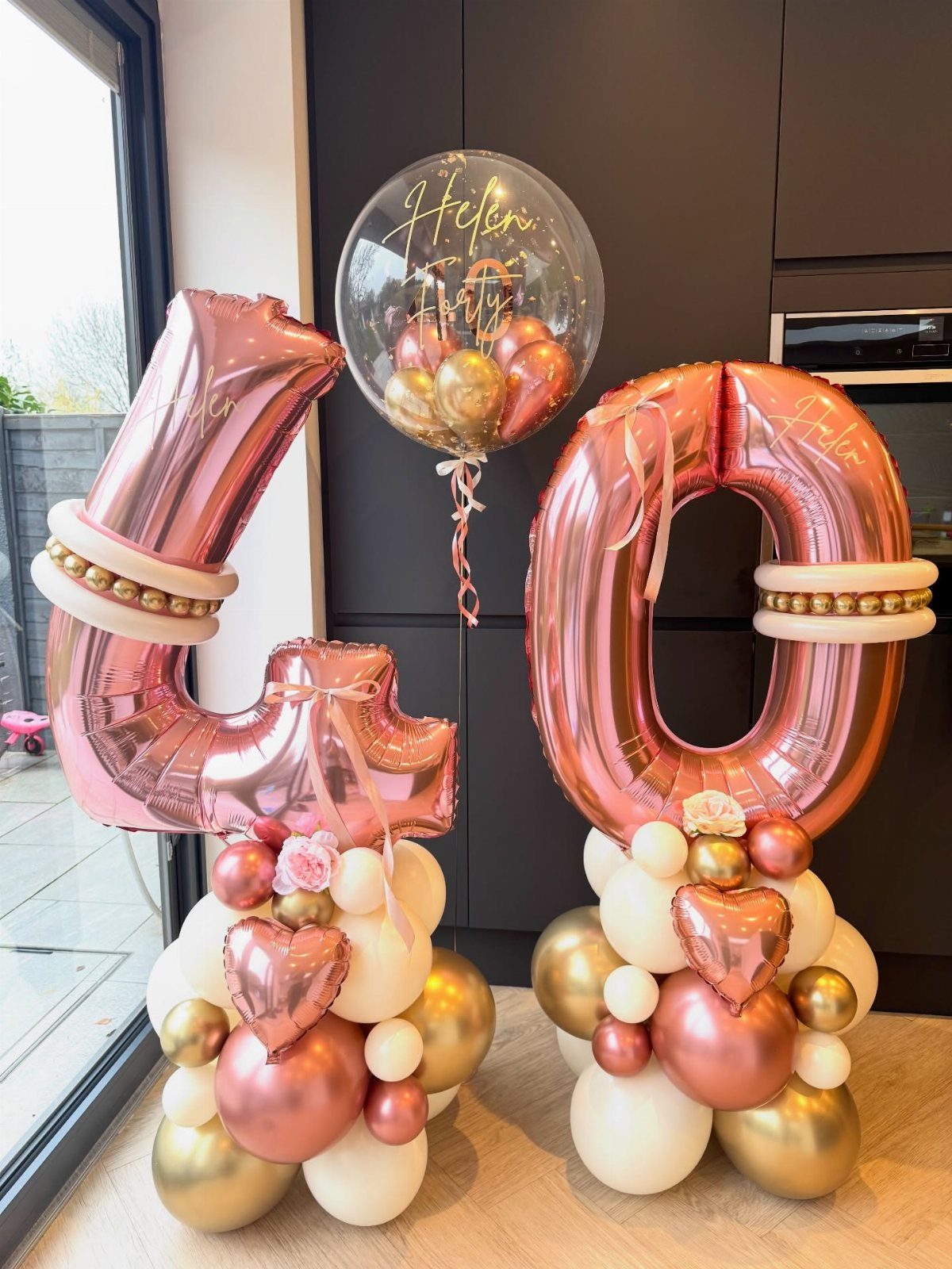 Rose gold number 40 balloons with gold and cream balloon clusters below.