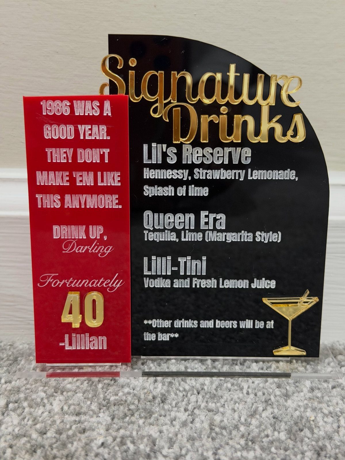Signature drinks sign and red 40th birthday card for Lillian on a carpet.