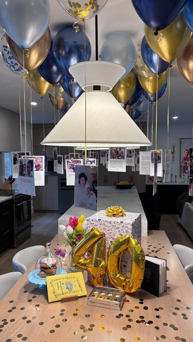 Gold number 40 balloons and party decorations on a table with hanging photos.