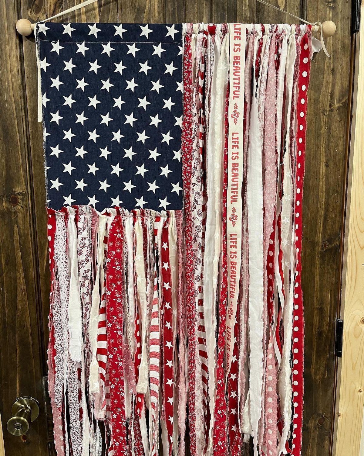 Handmade American flag wall hanging made from red, white, and blue fabric strips.