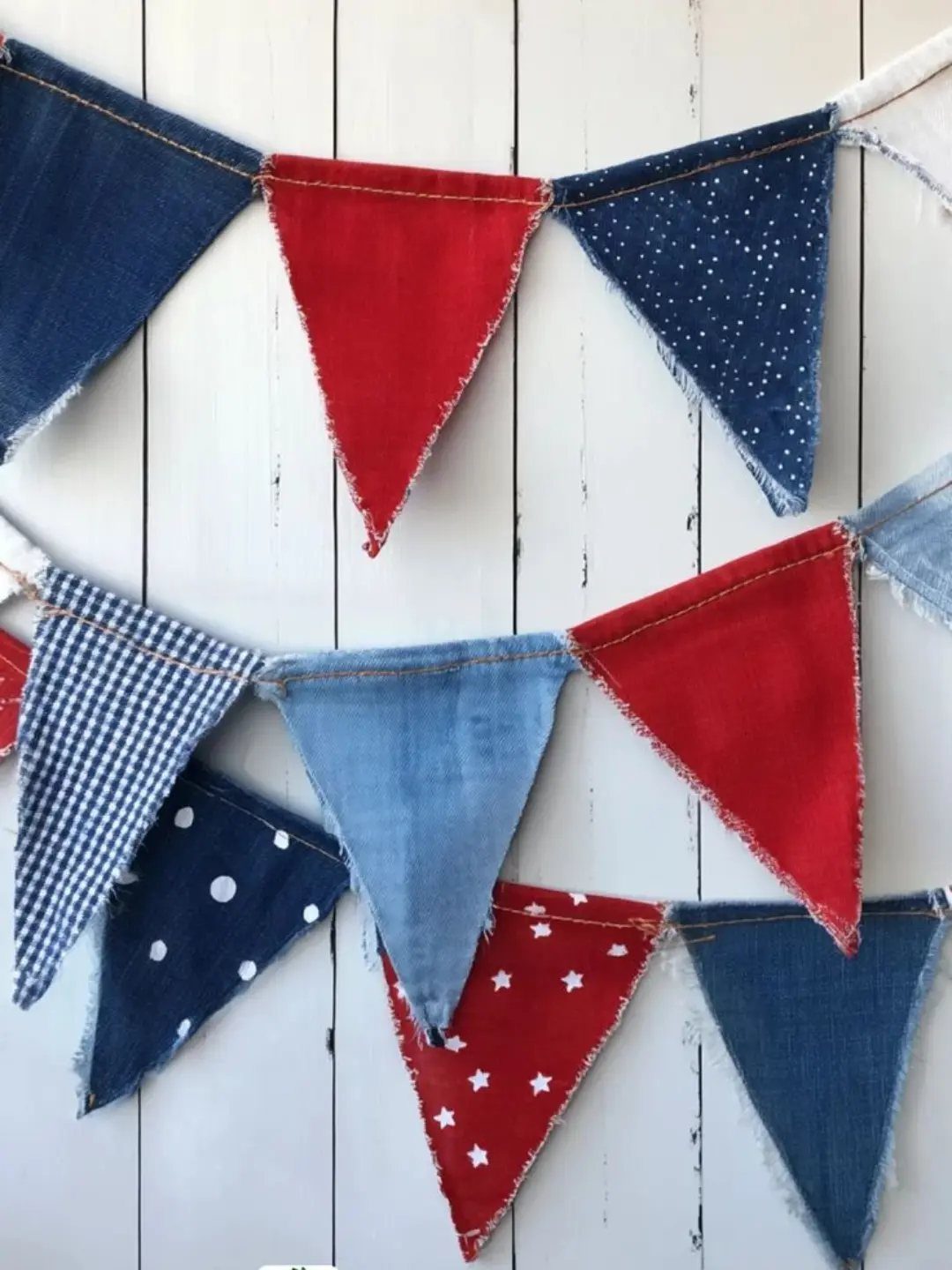 Patriotic bunting flags in red, white, and blue fabric hanging on a white wall.
