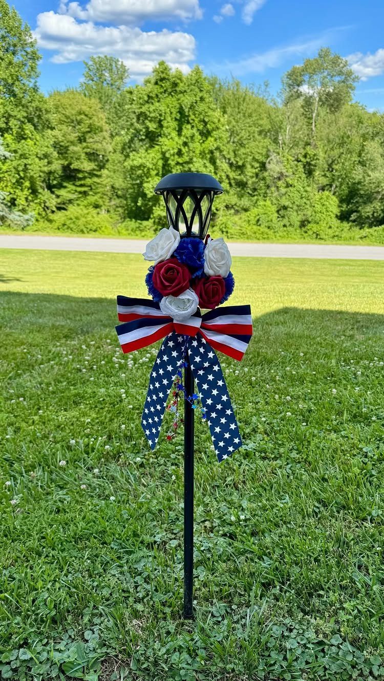 Tiki torch decorated with red white and blue flowers and a starred bow.
