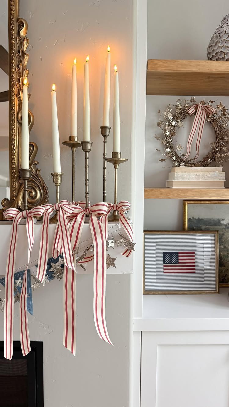 White mantel decorated with red and white striped ribbons, lit candles, and American flag.