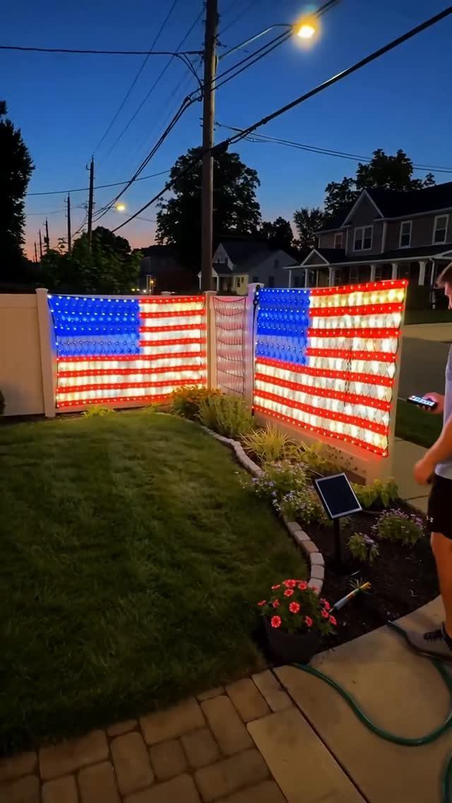 American flags made of red, white, and blue LED lights on a fence