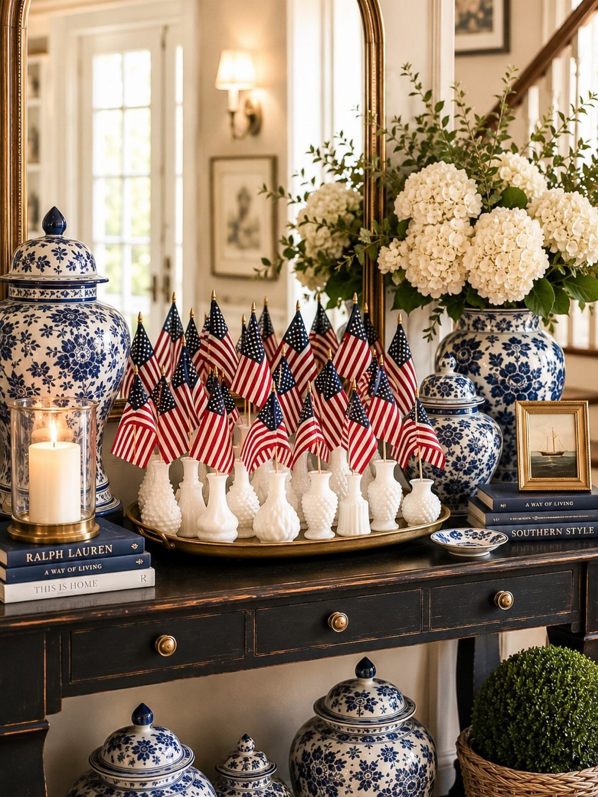 Small American flags in white vases on a gold tray atop a console table.