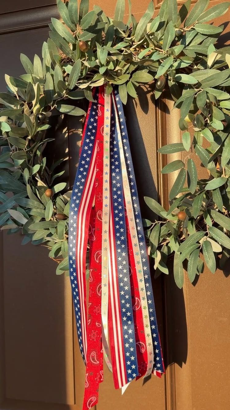 Olive leaf wreath with red, white, and blue patriotic ribbons on a door