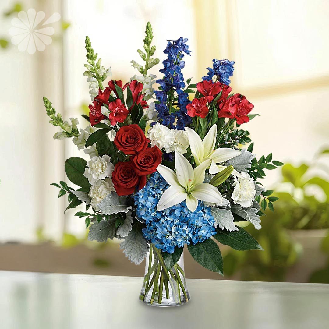 Red, white, and blue floral arrangement in a clear glass vase.