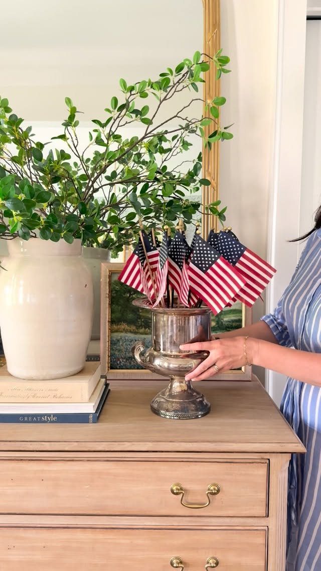 Silver vase filled with small American flags on a light wood dresser