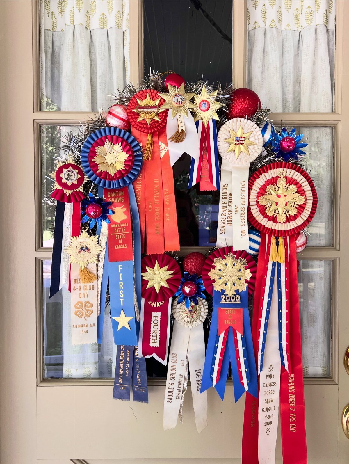 Patriotic wreath made of red, white, and blue award ribbons on a door