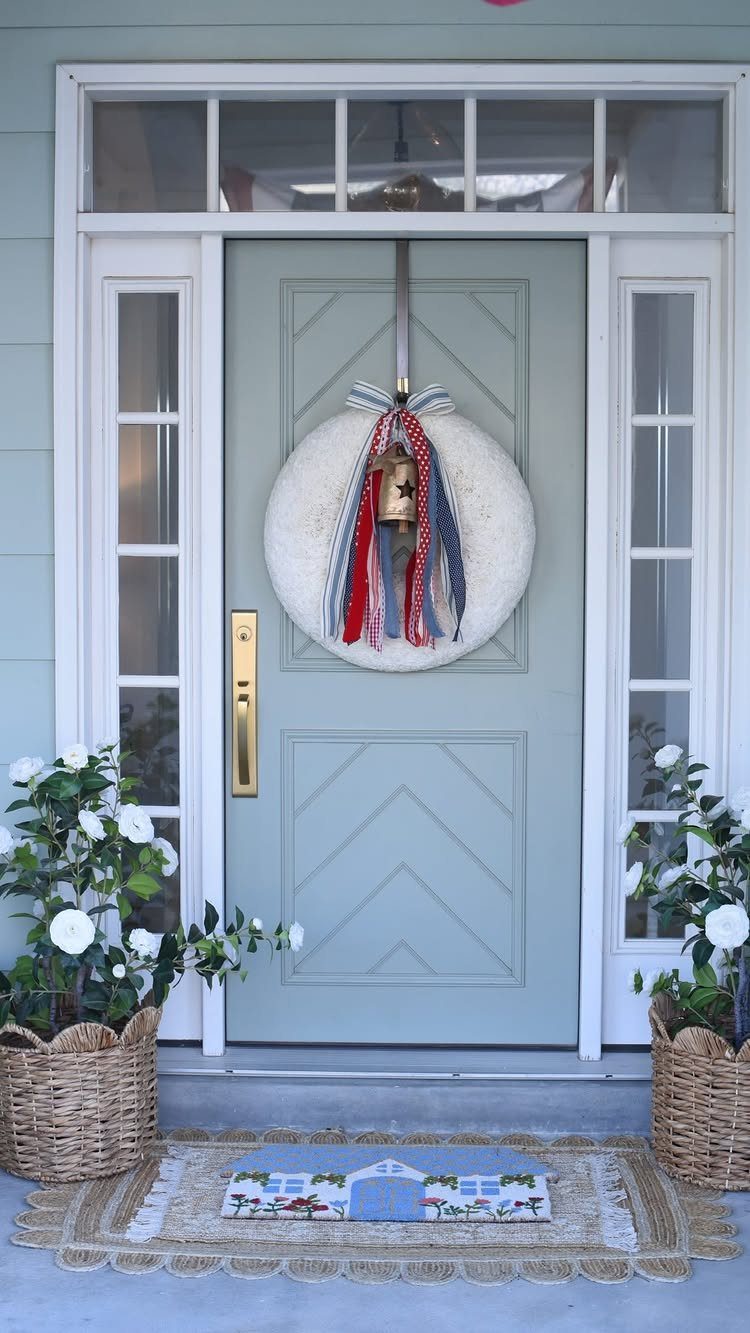 White circular wreath with patriotic ribbons on a light blue front door