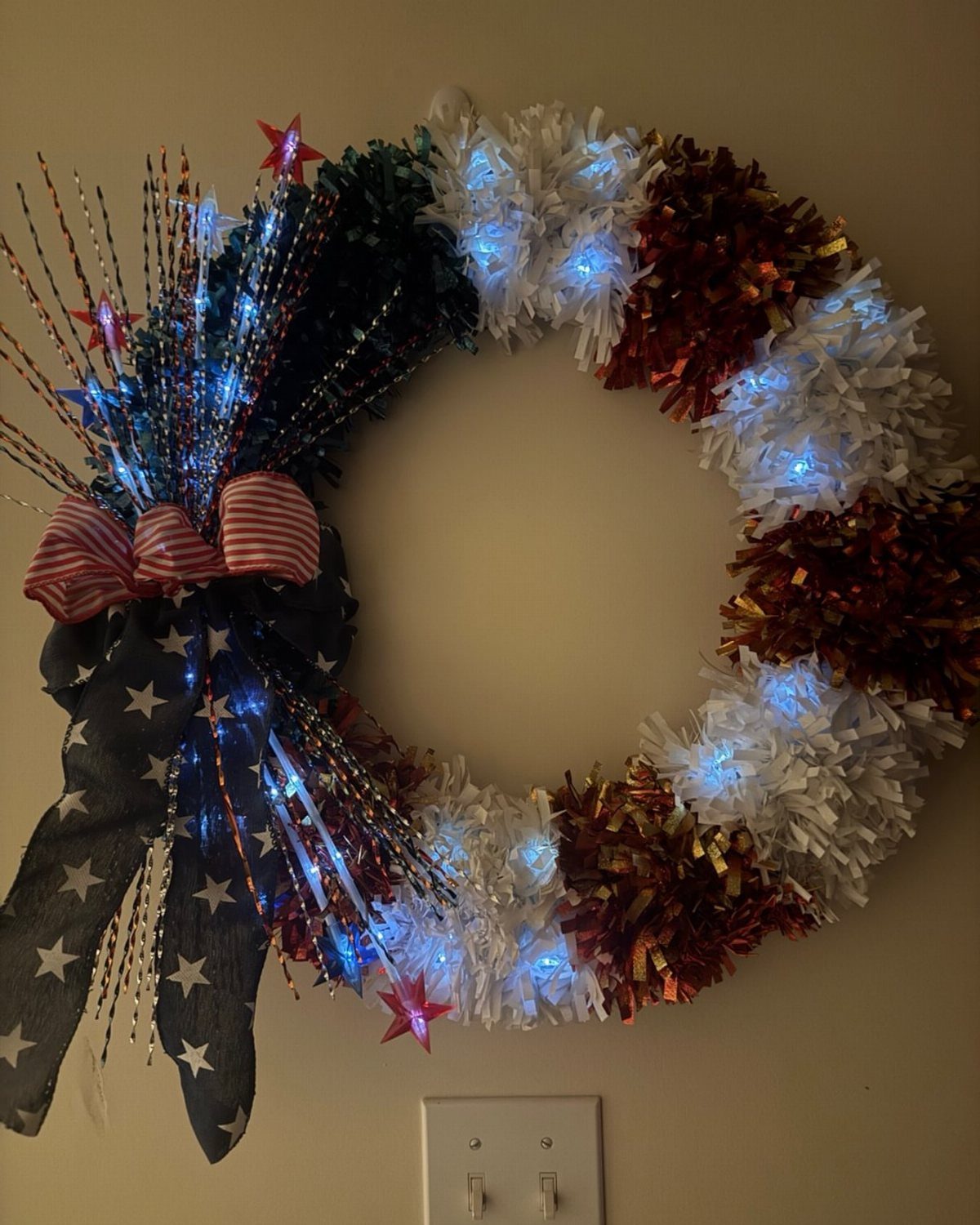Patriotic red, white, and blue tinsel wreath with fairy lights and stars.