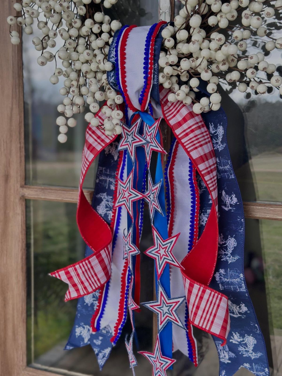 Patriotic wreath with white berries and red, white, and blue star ribbons.