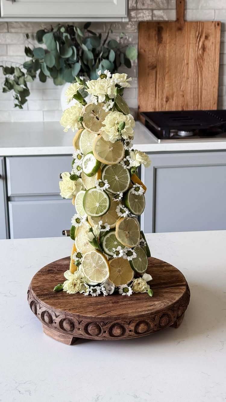 Citrus fruit tower with lemon and lime slices and white flowers on wood.