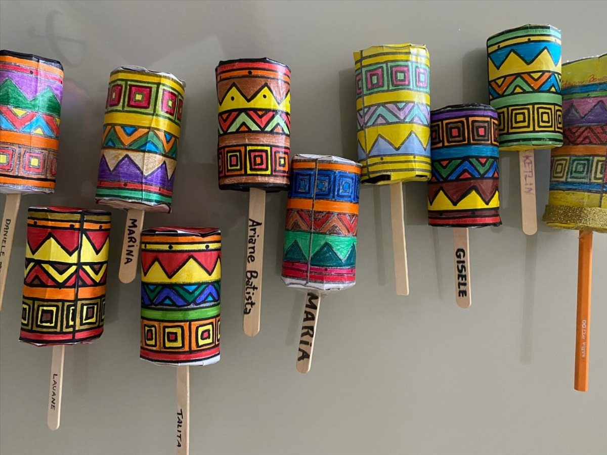 Handmade colorful maracas with geometric patterns on wooden sticks on a grey background