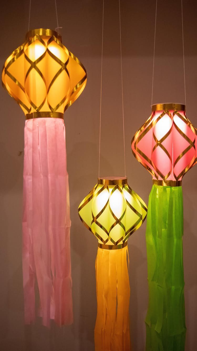 Colorful hanging lanterns with gold frames and long tissue paper tassels.