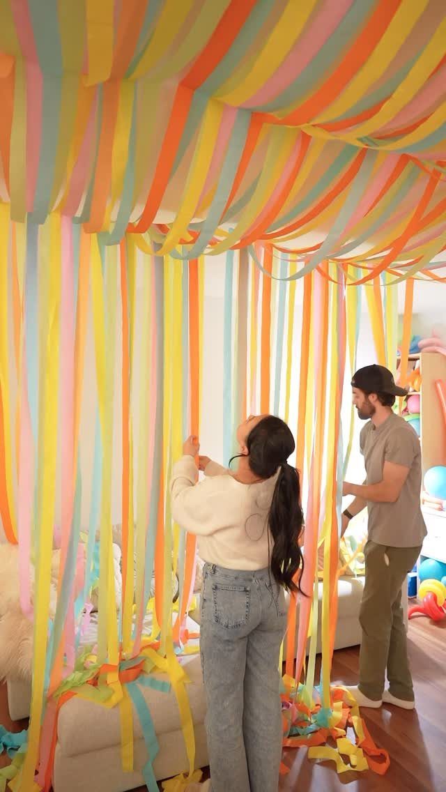 Colorful crepe paper streamers hanging from a ceiling and walls in a room.