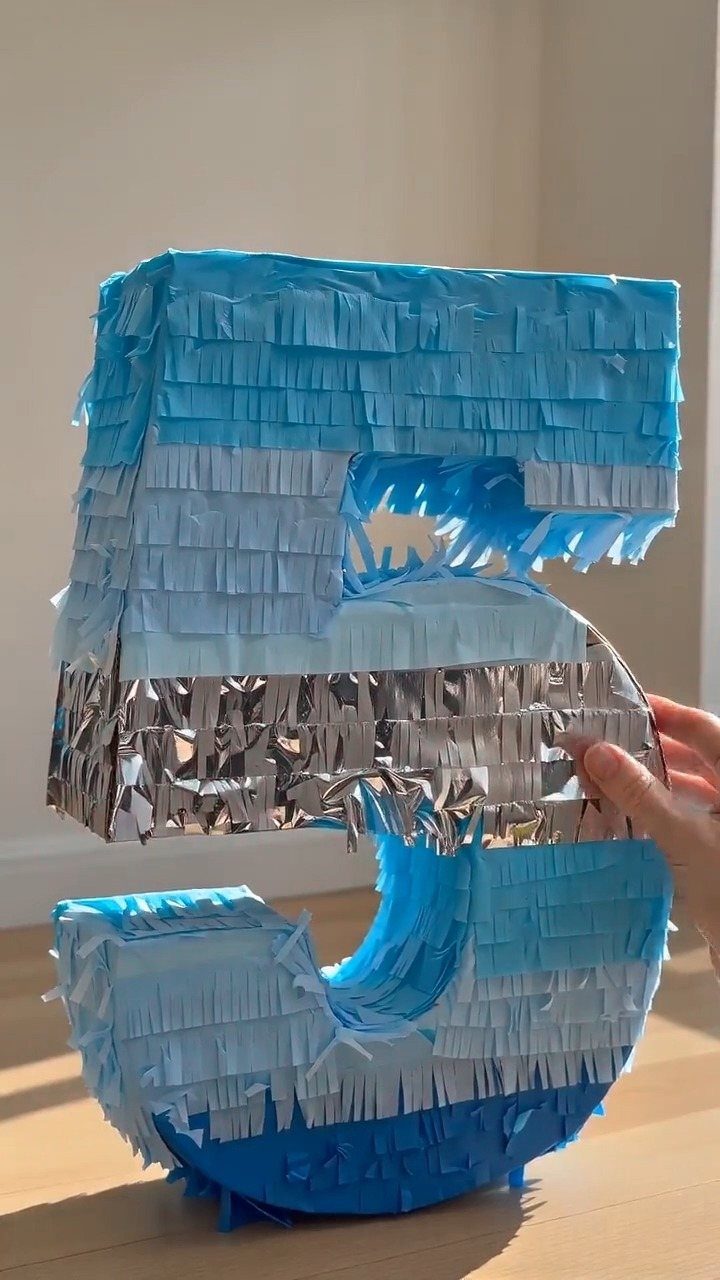 Large number five sculpture covered in blue and silver fringed foil tinsel.