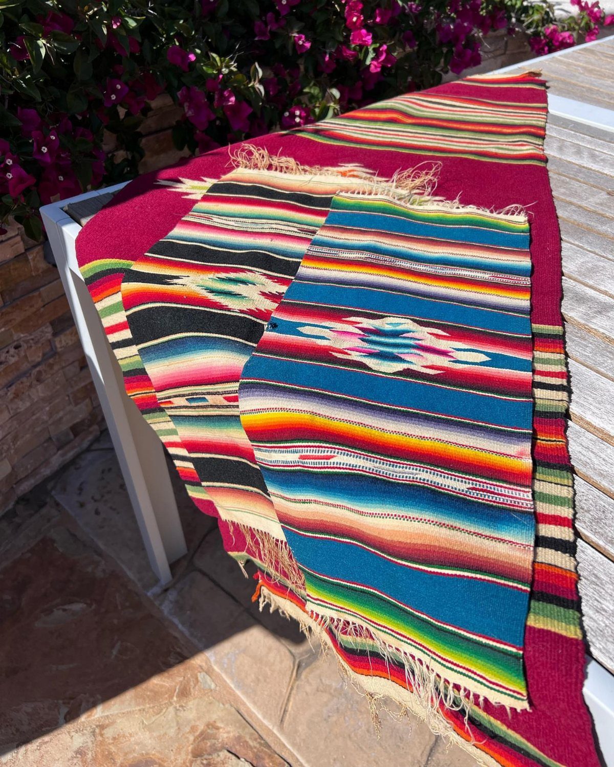 Colorful striped serape table runner with fringed edges on a white outdoor table.