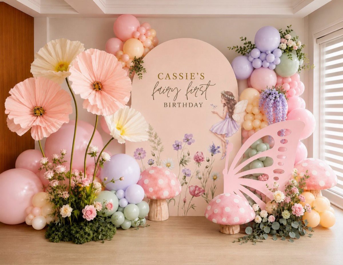 Birthday party backdrop with pastel balloons, giant paper flowers, and mushroom decorations.