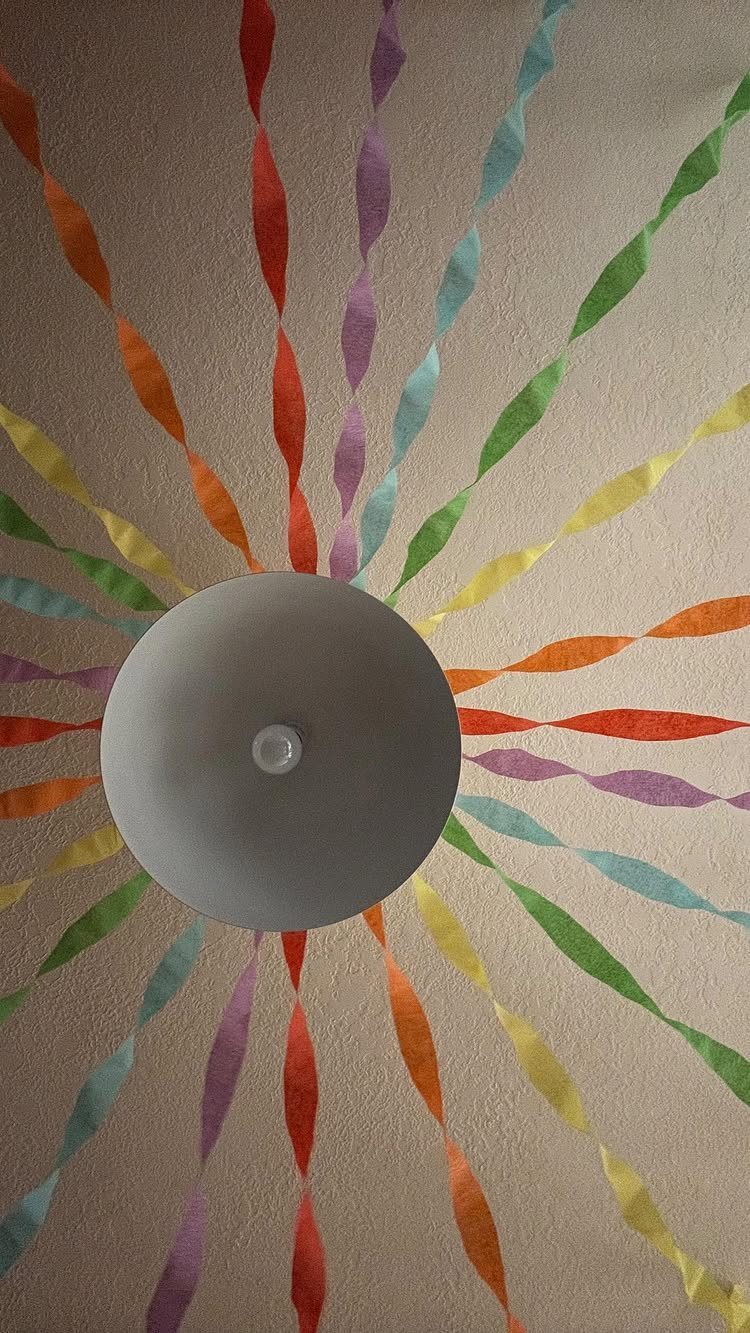Colorful twisted paper streamers radiating from a grey ceiling light fixture.