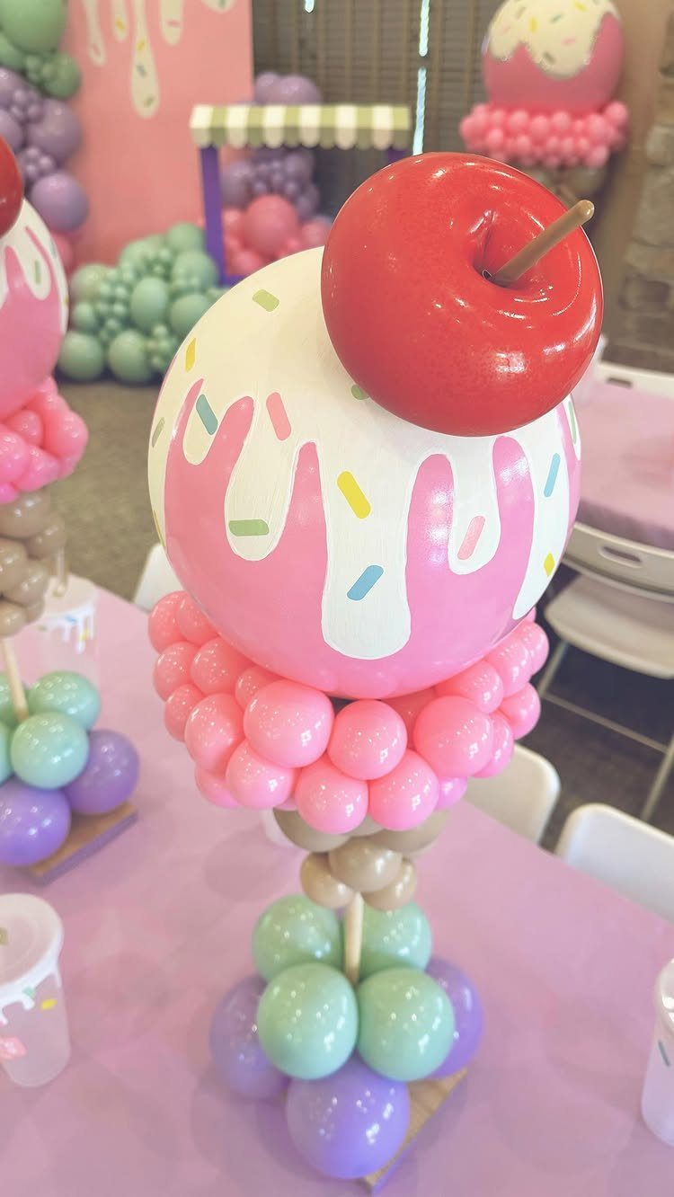 Ice cream sundae balloon sculpture with a red cherry on a pink table