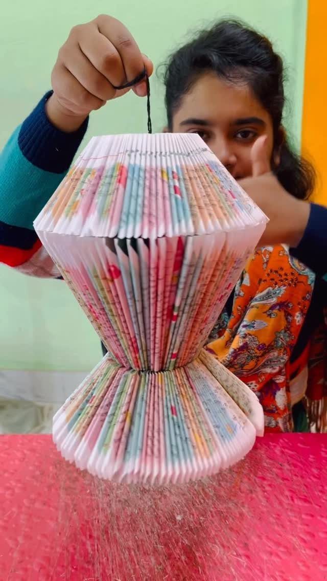 Handmade paper lantern made from recycled book pages held by a person.