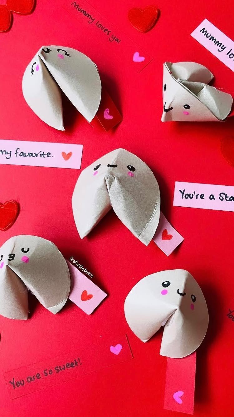 Paper fortune cookies with cute faces and messages on a red background