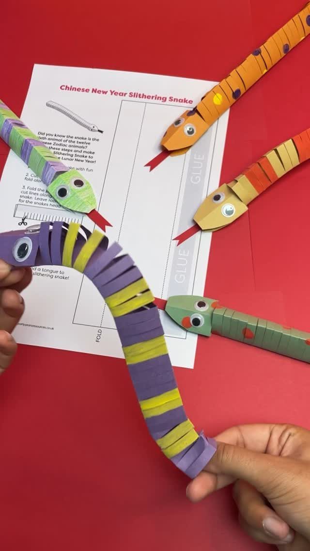 Colorful paper chain snakes with googly eyes on a red background with instructions.