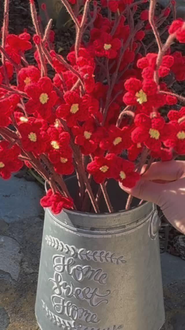 Red felt flowers on pipe cleaner stems in a metal Home Sweet Home bucket