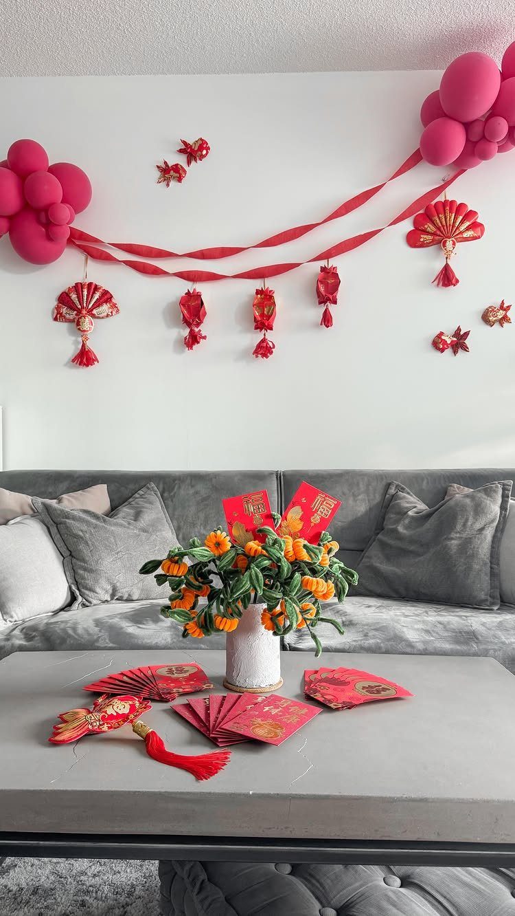 Chinese New Year decorations including red balloons, streamers, and fans in a living room