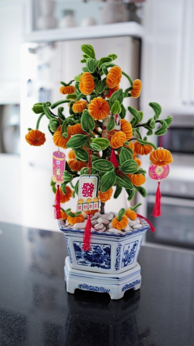 Decorative Chinese New Year bonsai tree with orange flowers and red ornaments in ceramic pot