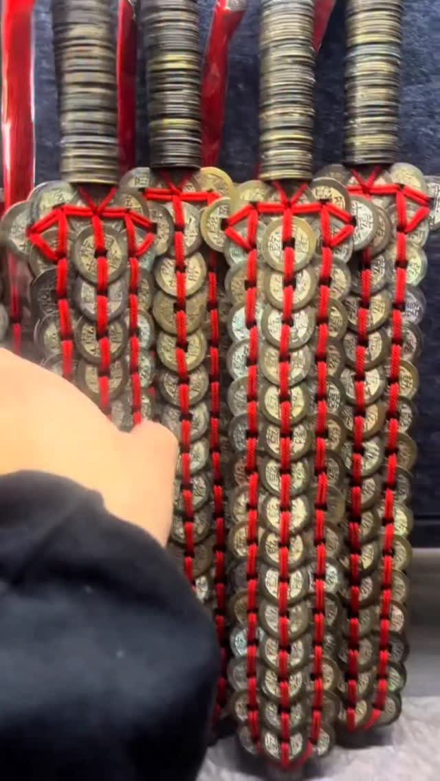 Gold Chinese coins tied with red cords hanging in vertical decorative strings.