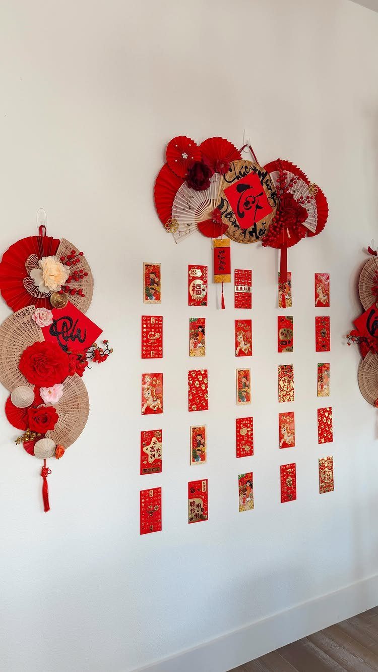 Red and gold Chinese New Year decorations with fans and envelopes on a wall