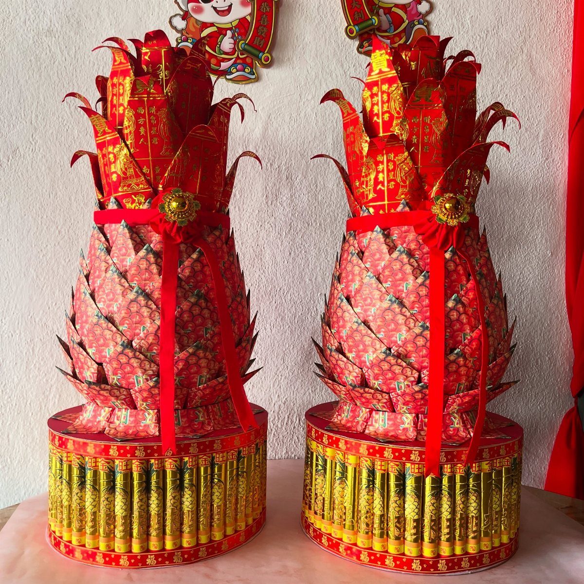 Two red and gold paper pineapple sculptures on decorative gold bases.