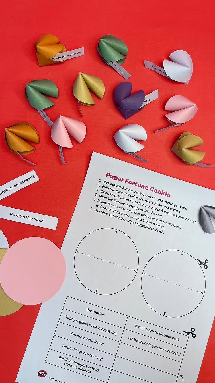 Colorful folded paper fortune cookies with slips of paper on a red background.