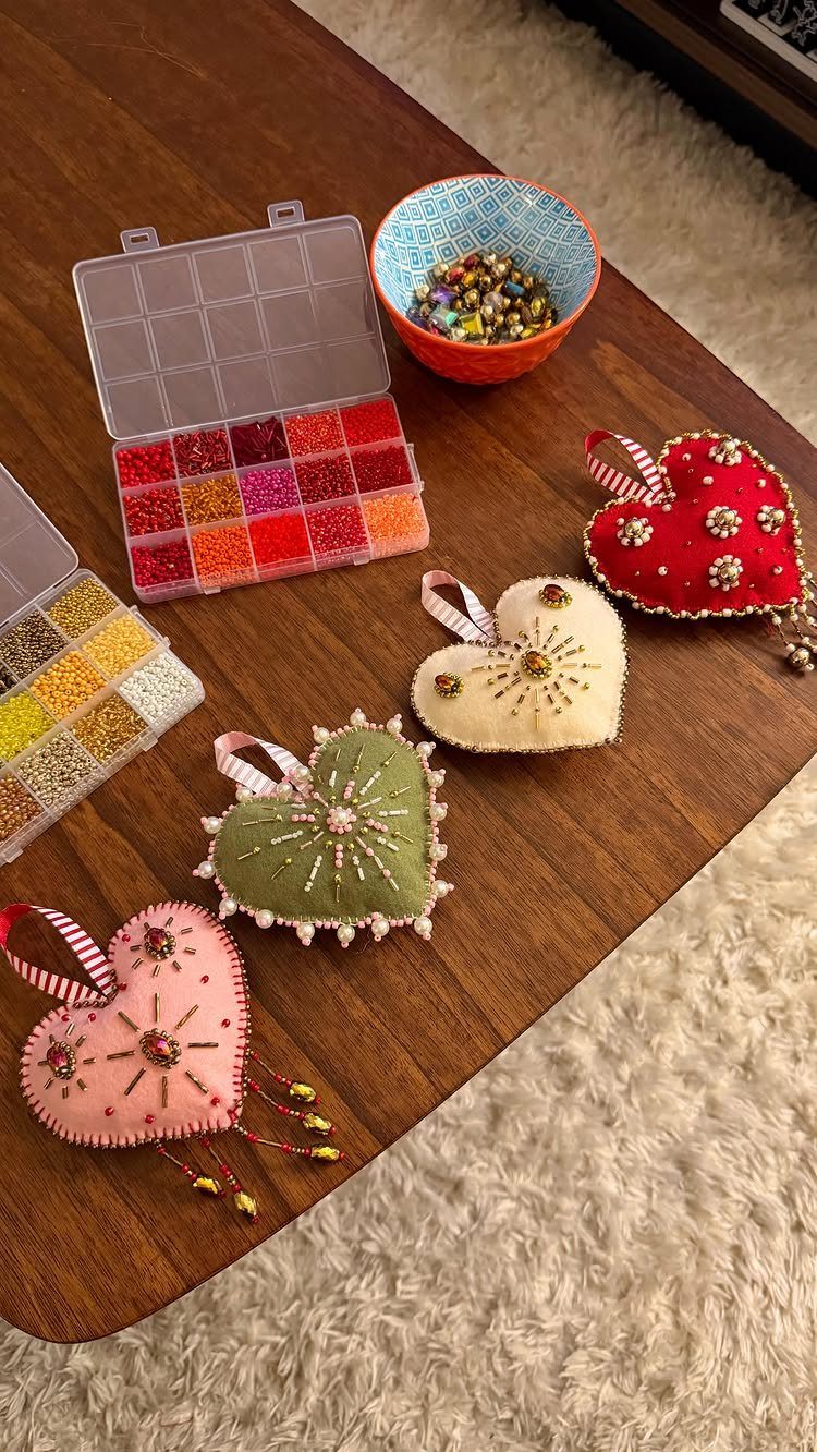 Heart-shaped fabric ornaments decorated with beads and sequins on a wooden table.