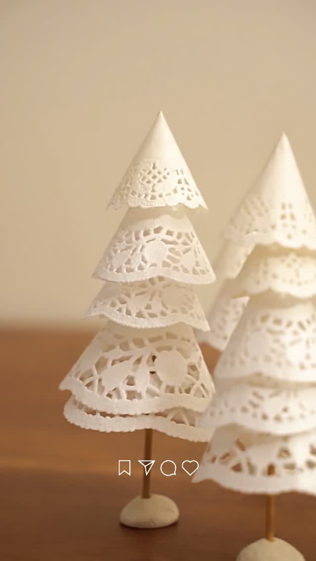 White paper doily Christmas trees with lace patterns on wooden stands.