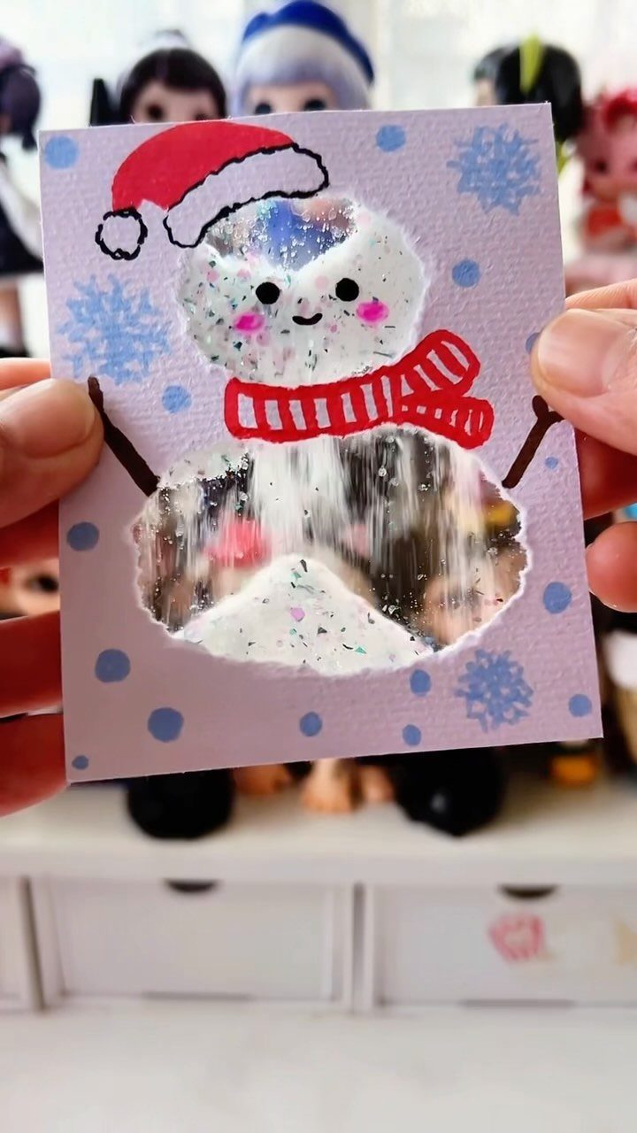 Handmade snowman card with a glittery snow globe cutout and red accessories