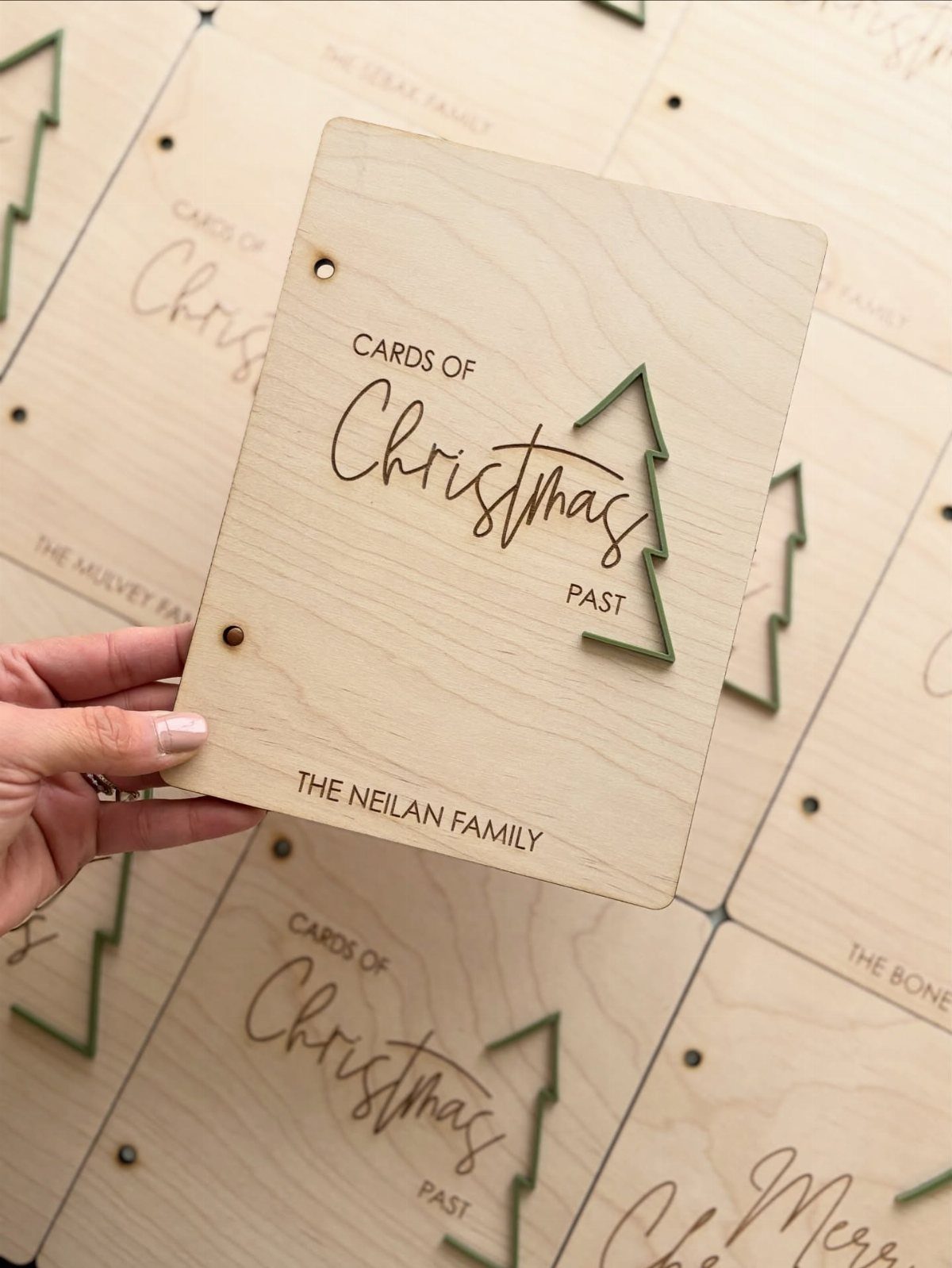 Wooden plaque engraved with Christmas text and a small green tree cutout.