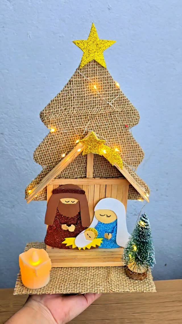Wooden nativity scene with stylized figures set against a burlap Christmas tree backdrop.
