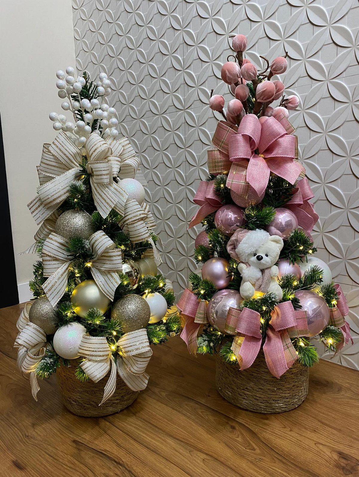 Two mini Christmas trees decorated with bows and ornaments in woven baskets.