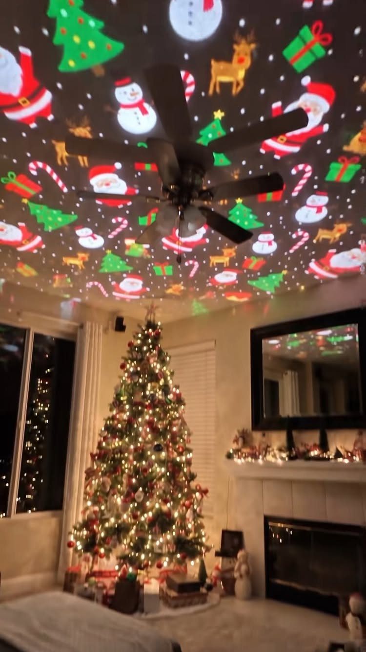 Christmas tree and fireplace with holiday projections of Santa and snowmen on the ceiling