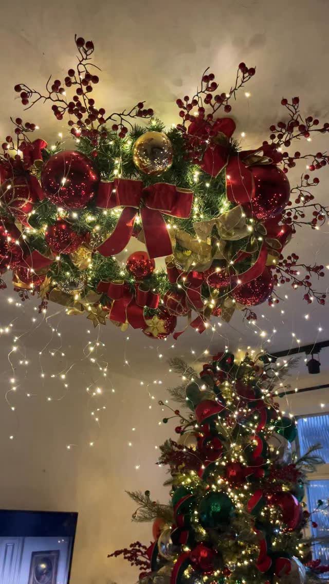 Christmas tree and ceiling wreath decorated with red ornaments and warm white lights.