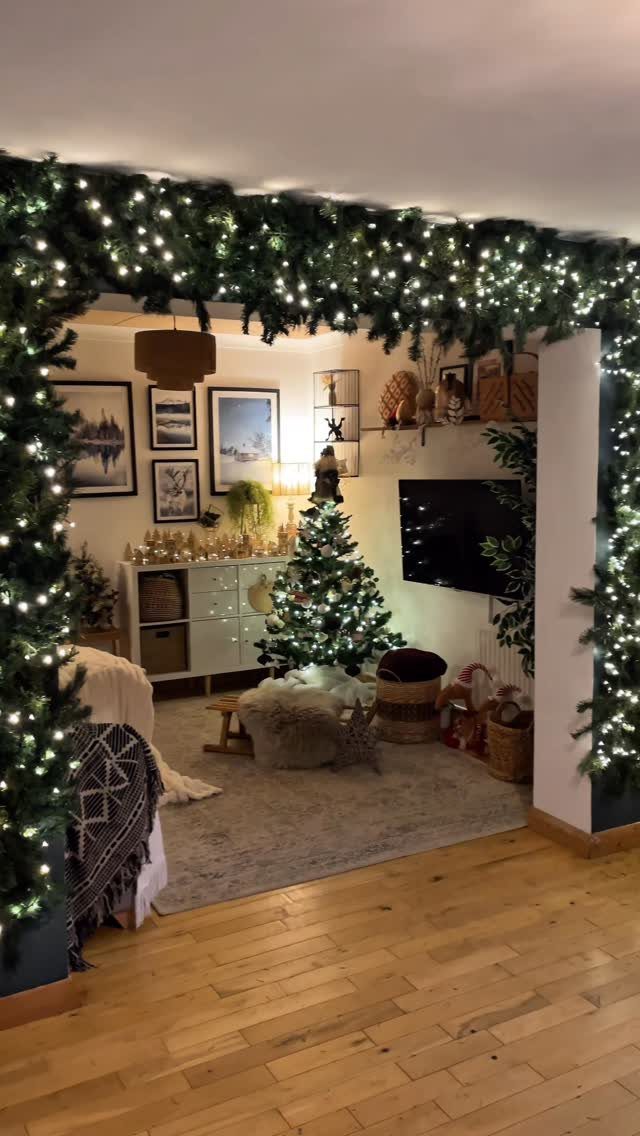 Christmas living room with a lit tree and garland framing the doorway entrance