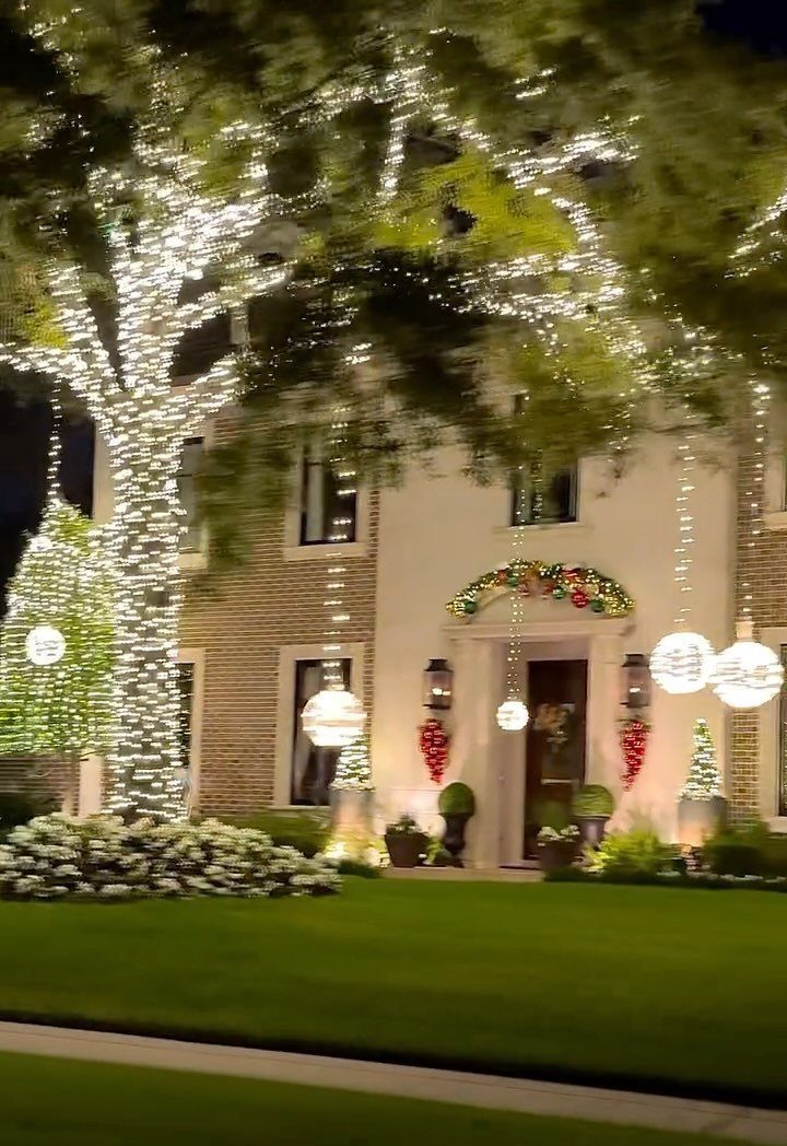 House exterior decorated with white fairy lights on a tree and glowing spheres.