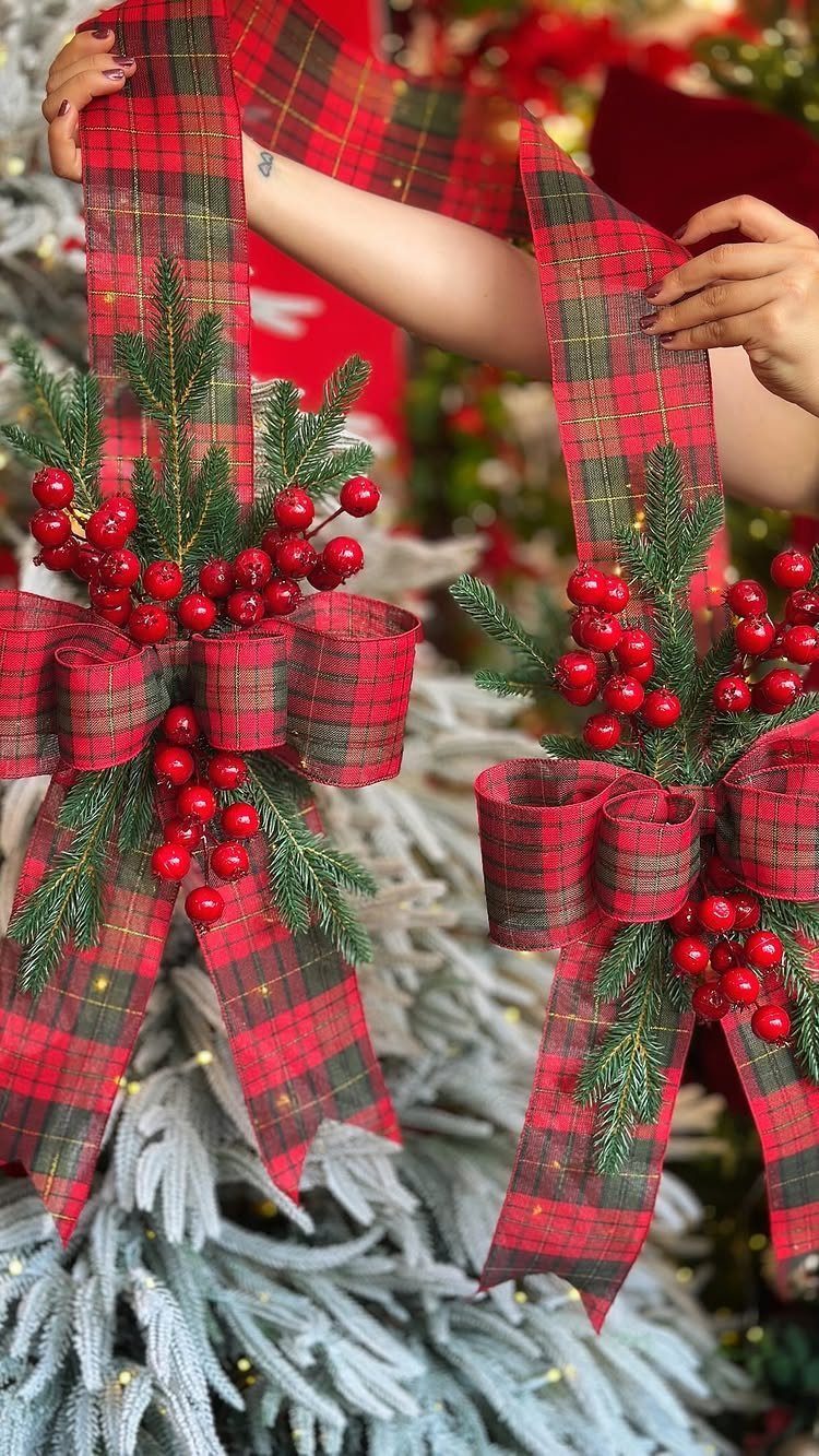 Red and green plaid ribbons with berries and pine needles on a frosted tree